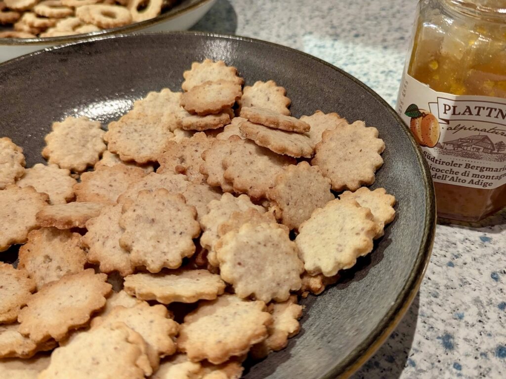 Ein Teller mit Kekshälften und ein Glas Marmelade