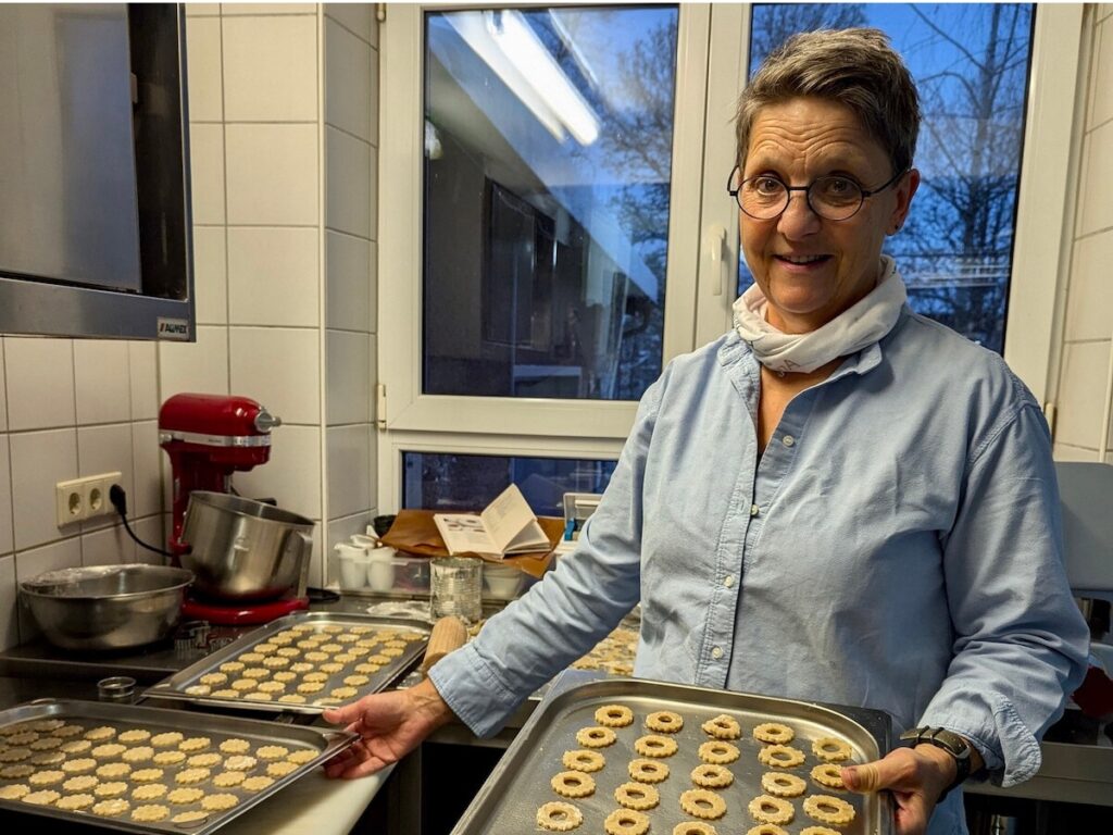 Astrid in der Küche mit einem Backblech mit Keksen darauf in der Hand